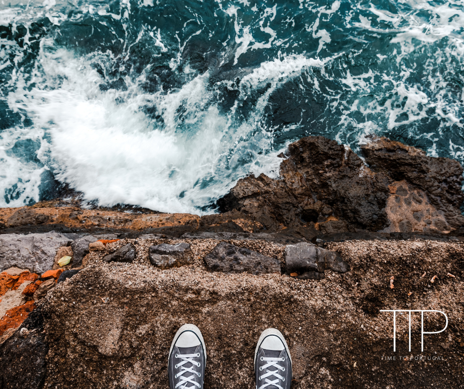 pair of shoes on top of cliff, ocean.