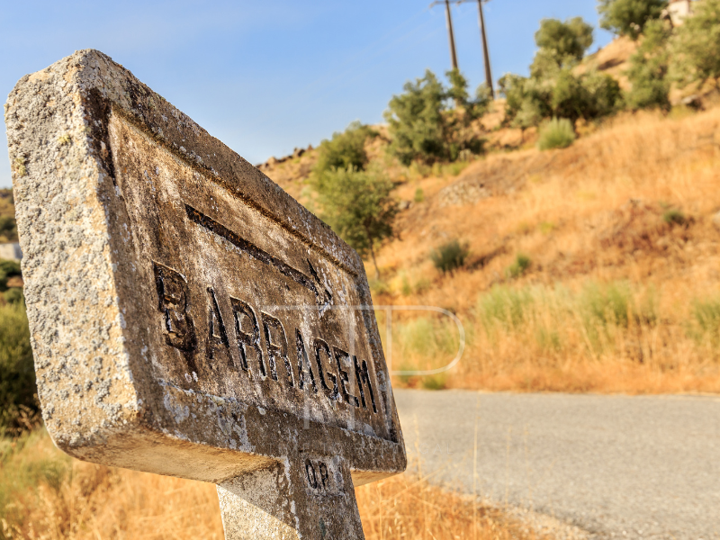Stone sign with word Barragem beside a road