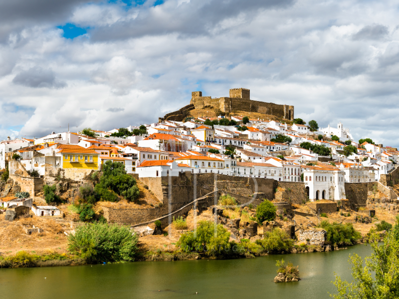 A fortress and white old houses at a river