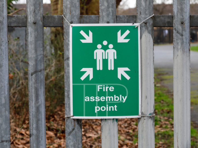 Wooden fence with a green, white sign for meeting point