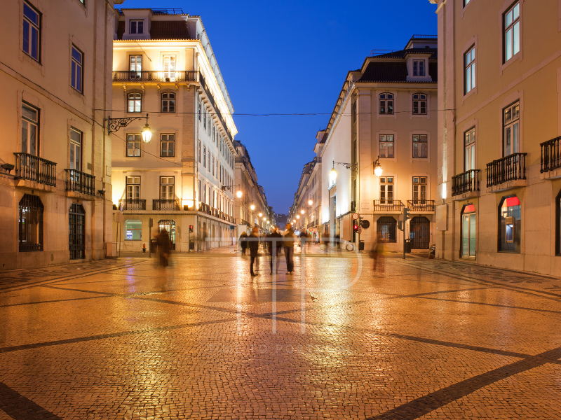 Lit street at night with buildings and some people