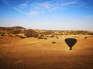 Dry grass country site with the shadow of a hot air balloon