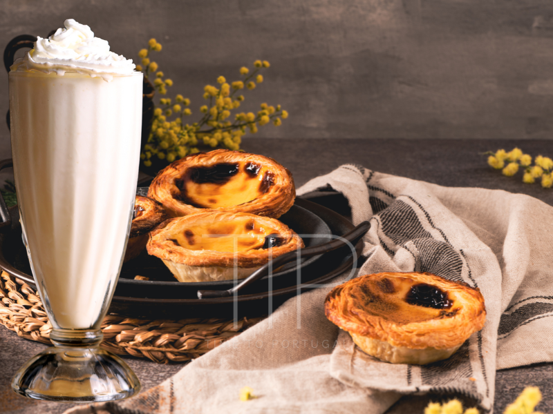 A glass filled with milkshake and pastries on a table.