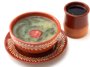 Clay bowl with green soup and a clay cup with red wine